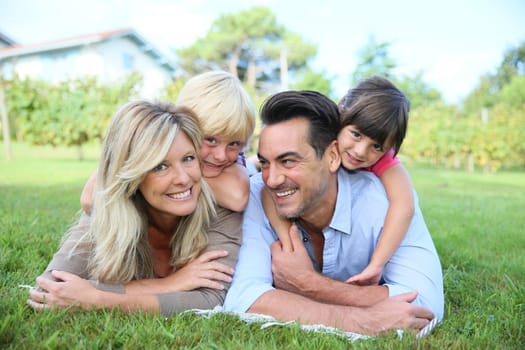 Family of four laying on grass in front of house