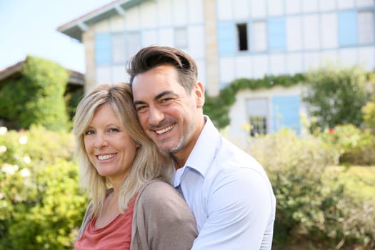 Cheerful mature couple standing in front of house