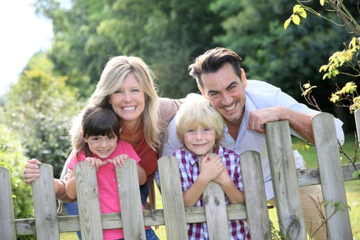 Happy family leaning on fence by country home