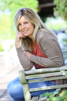 Mature blond woman relaxing in outdoor bench