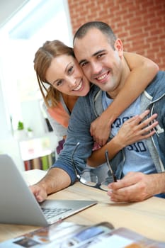 Cheerful couple websurfing on internet with laptop