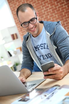 Guy with eyeglasses using smartphone at home