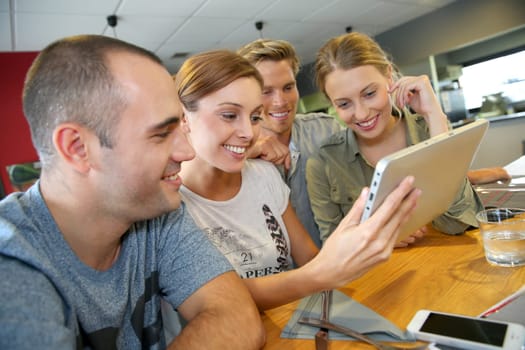 Group of friends in campus lounge websurfing with tablet