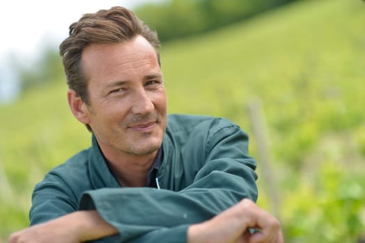 Smiling vinegrower standing in vineyard