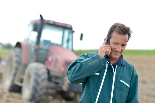 Farmer walking in field and talking on mobile phone