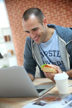 Student eating sandwich in front of laptop