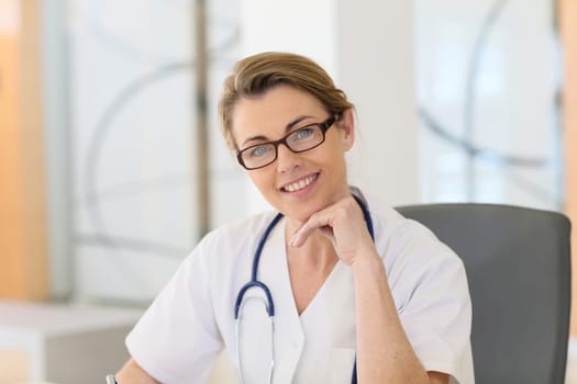 Portrait of mature nurse sitting at desk in office