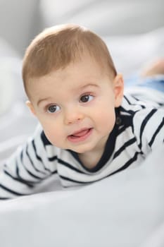 Cheerful baby boy laying over bed