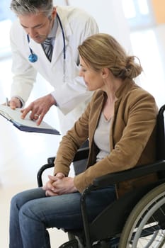Doctor talking to woman in wheelchair after surgery