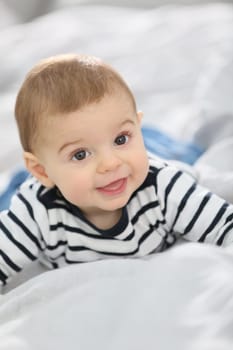 Cheerful baby boy laying over bed