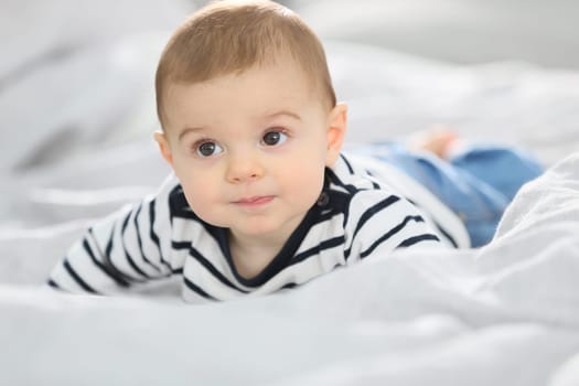 Cheerful baby boy laying over bed
