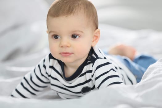 Cheerful baby boy laying over bed