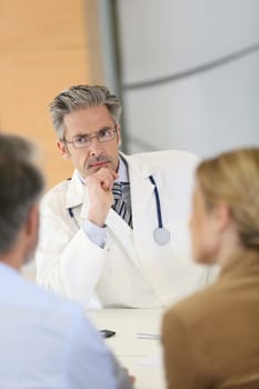 Doctor meeting couple in hospital office