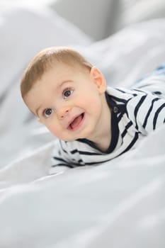 Cheerful baby boy laying over bed