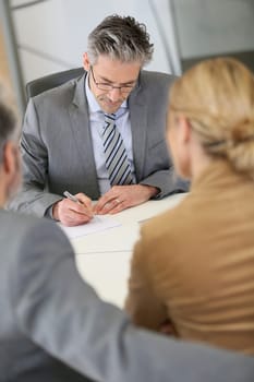 Mature couple signing contract in lawyer's office