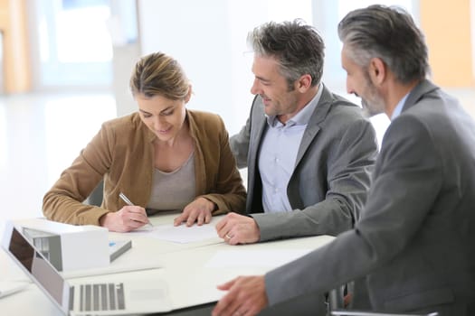 Mature couple signing construction contract in architect's office