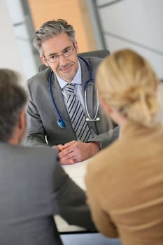Senior doctor listening to patients in office