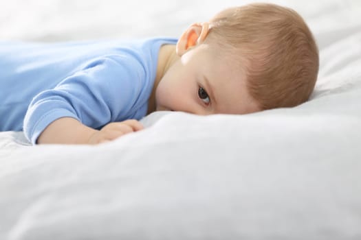8-month-old baby boy laying on bed