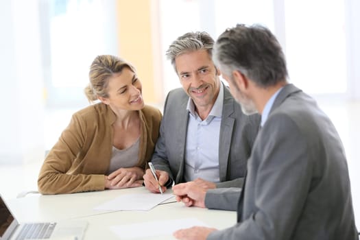 Mature couple signing financial contract at the bank