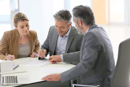Mature couple signing construction contract in architect's office