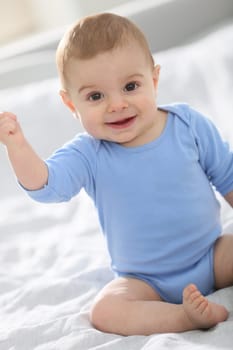 Cute baby boy sitting on bed
