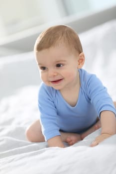 Cute baby boy sitting on bed