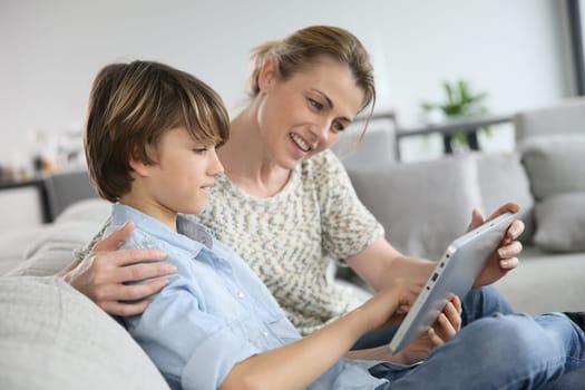 Mother and son playing with digital tablet at home