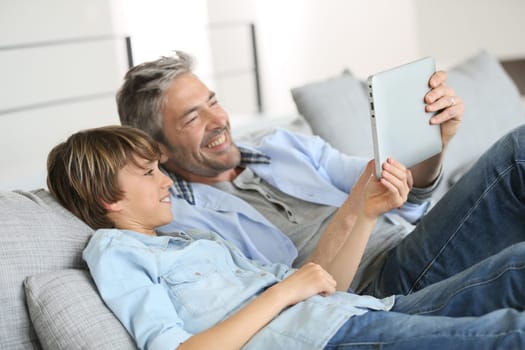 Daddy and son websurfing on digital tablet at home