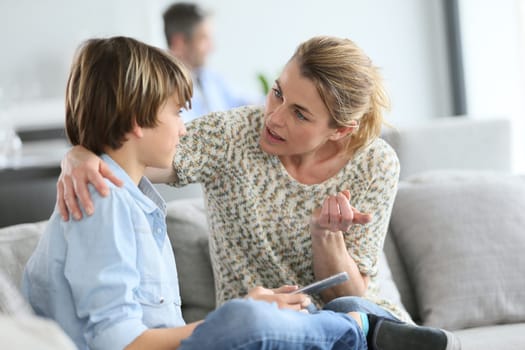 Mother giving warning to young boy using smartphone