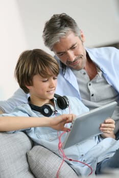 Father watching kid playing with tablet