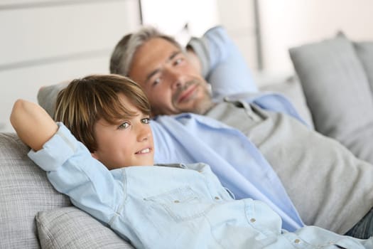 Father and son relaxing in sofa a thome