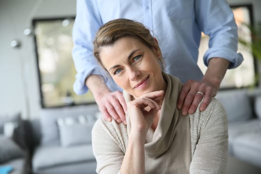 Portrait of mature woman, husband's hands on shoulders