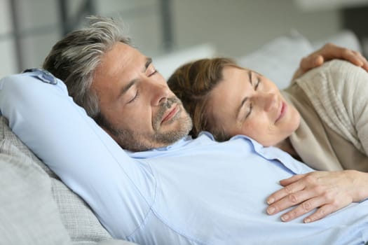 Mature couple having a rest laying down in sofa