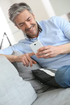 Mature man sending message with smartphone