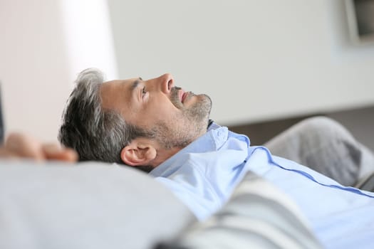Middle-aged man having a restful moment relaxing in sofa