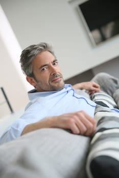 Mature man in living-room, relaxing in sofa