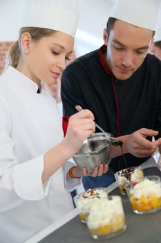 Chef with student in pastry making dessert
