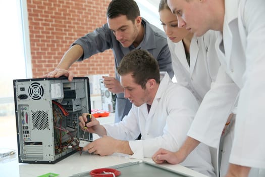 Students in computing class with teacher fixing hardware