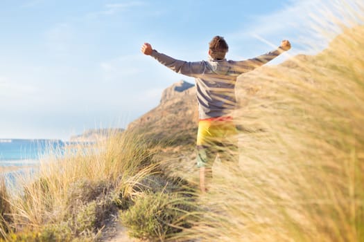 Sporty active man, arms rised, enjoying beauty of nature, freedom and life at beautiful landscape. Active lifestyle outdoors. Made it.