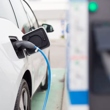 Power supply for electric car charging.  Electric car charging station. Close up of the power supply plugged into an electric car being charged.