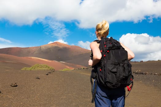 Woman hiking in nature can see the peak of Timanfaya volcano, nearly made it to top.
