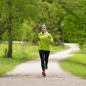 Sporty young female runner in city park.  Running woman. Female runner during outdoor workout in nature. Fitness model outdoors. Weight Loss. Healthy lifestyle.