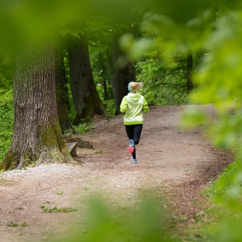 Sporty young female runner in forest.  Running woman. Female runner during outdoor workout in nature. Fitness model outdoors. Weight Loss. Healthy lifestyle.