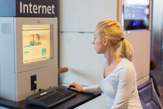 Young caucasian woman using comupter with public internet access point on airport.