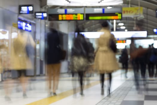 Corporate business people commuting to work by Tokyo public transport. Unrecognizable people blured in motion while rushing to train platforms.