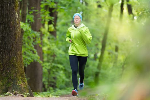 Sporty young female runner in forest.  Running woman. Female runner during outdoor workout in nature. Fitness model outdoors. Weight Loss. Healthy lifestyle.
