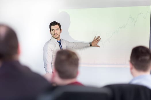 Business man making a presentation at office. Business executive delivering a presentation to his colleagues during meeting or in-house business training, explaining business plans to his employees.