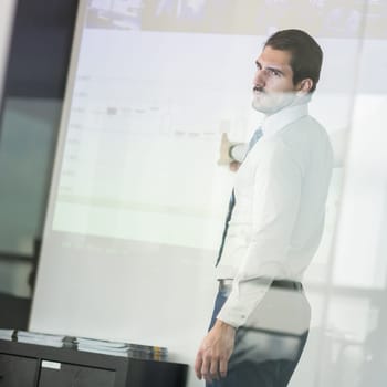 Businessman making a presentation in front of whiteboard. Business executive delivering a presentation to his colleagues during meeting or in-house business training.