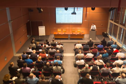 Speaker giving a talk in conference hall at business event. Audience at the conference hall. Business and Entrepreneurship. Tilt shift blur efect.