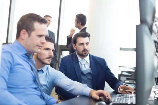 Business team looking at data on multiple computer screens in corporate office. Business people trading online. Business, entrepreneurship and team work concept.